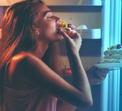 Девушка ночью ест пирожное из холодильника